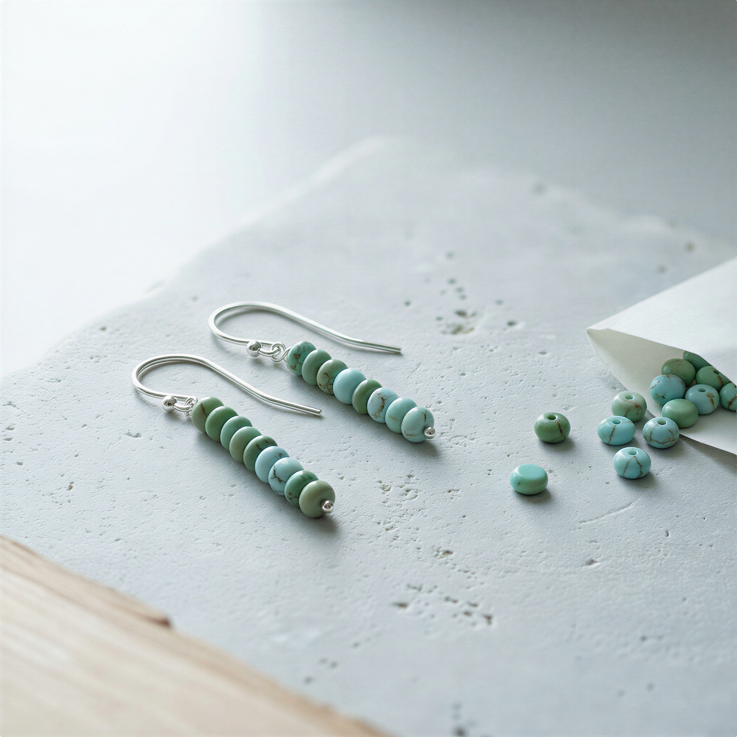Sterling silver earwires with tiny 1.5mm ball resting on linen surface in soft natural daylight