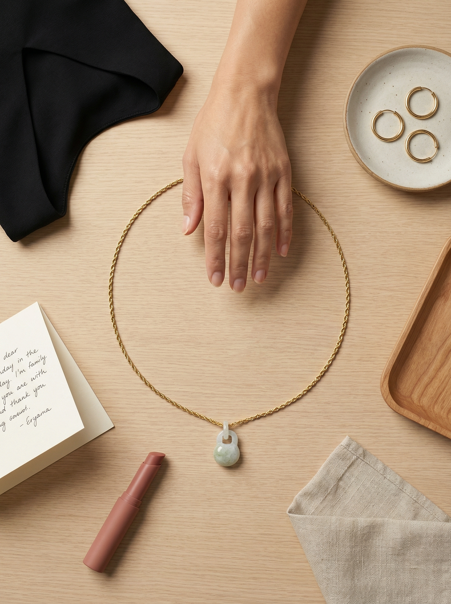 Overhead flat lay of gold rope necklace with hand hovering over curated wardrobe objects