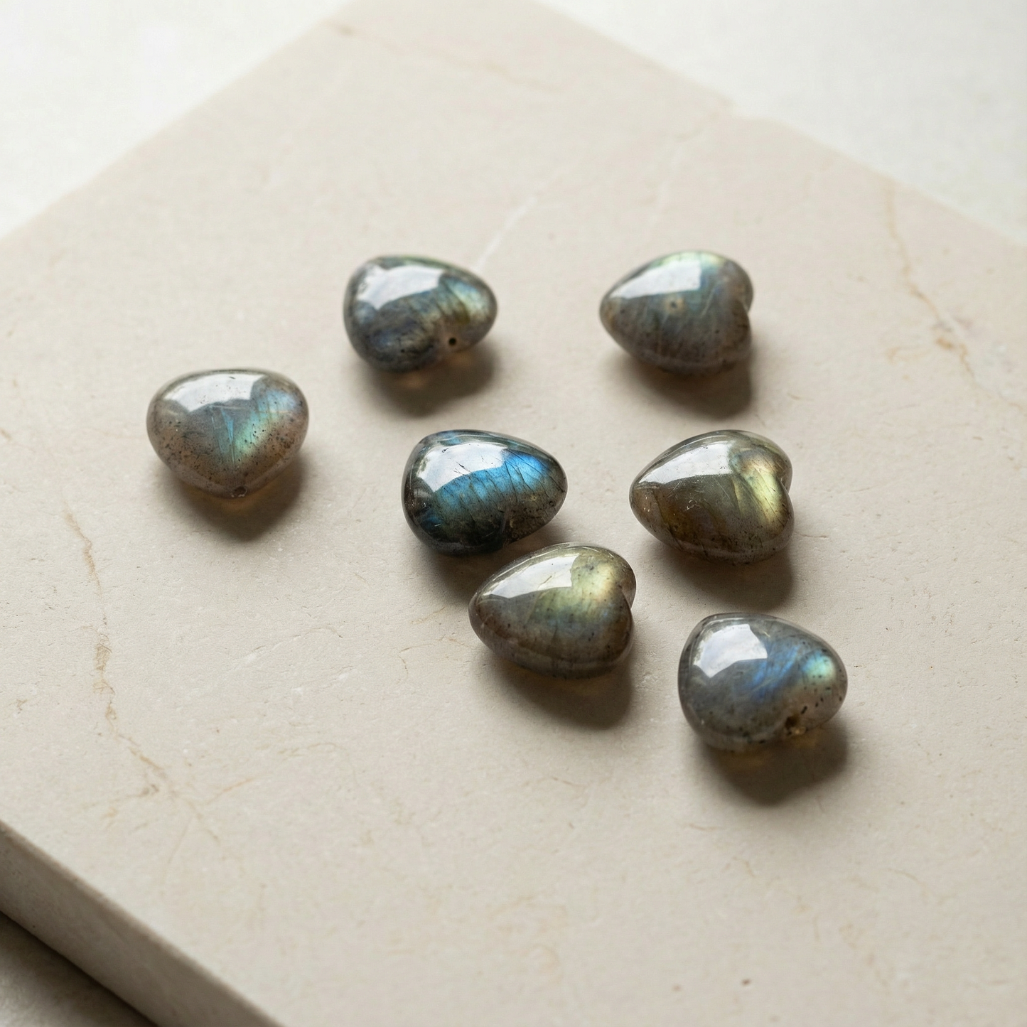 Polished labradorite heart bead resting on soft neutral surface with balanced light and refined minimal styling