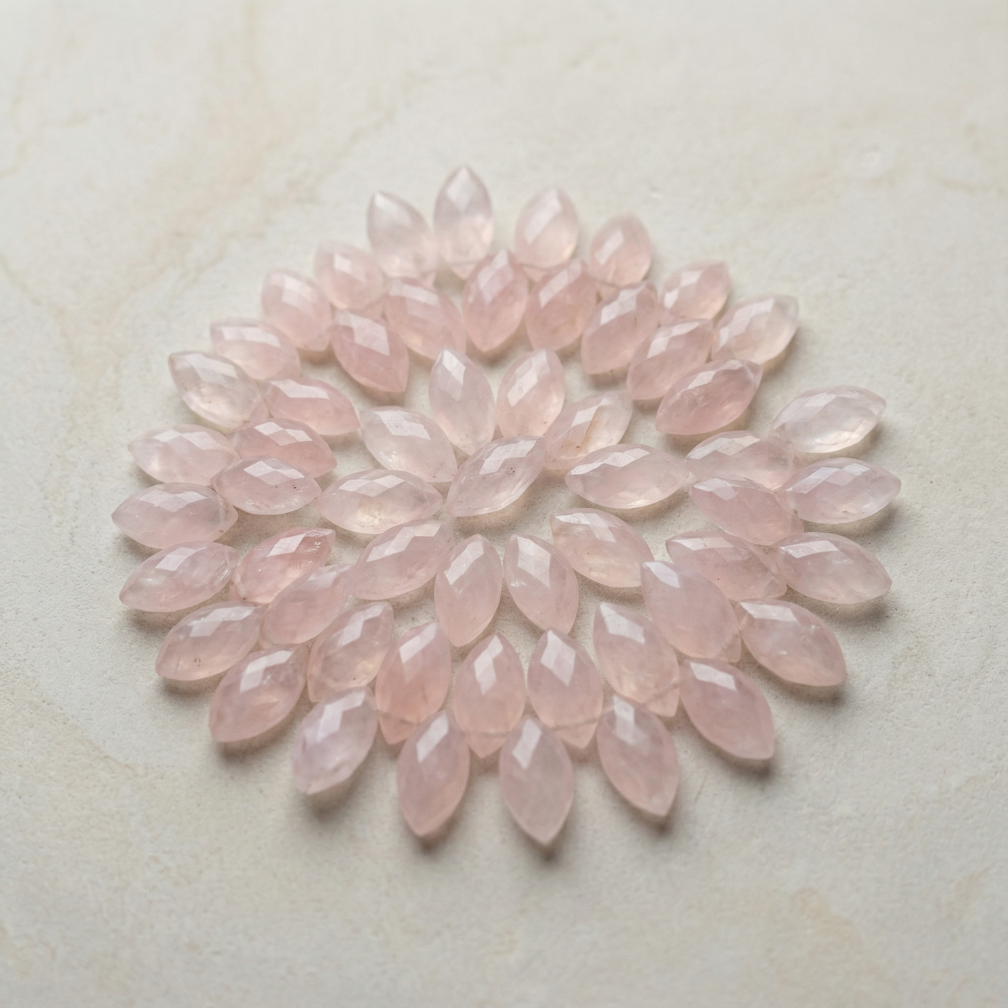 Faceted rose quartz marquise bead resting on natural stone surface with soft desert light and serene tones