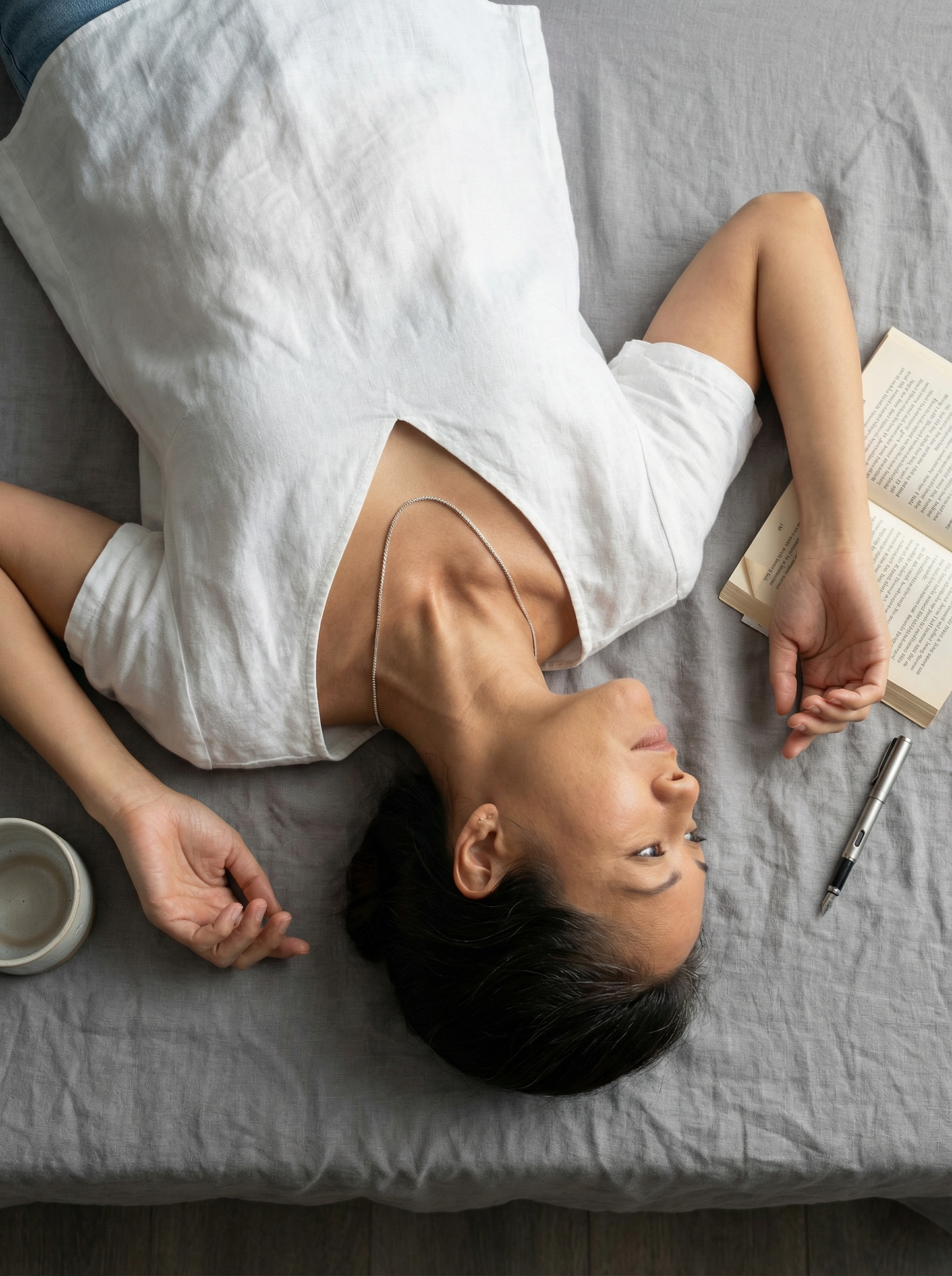Overhead view of reclining model with sterling silver box chain and linen still life.