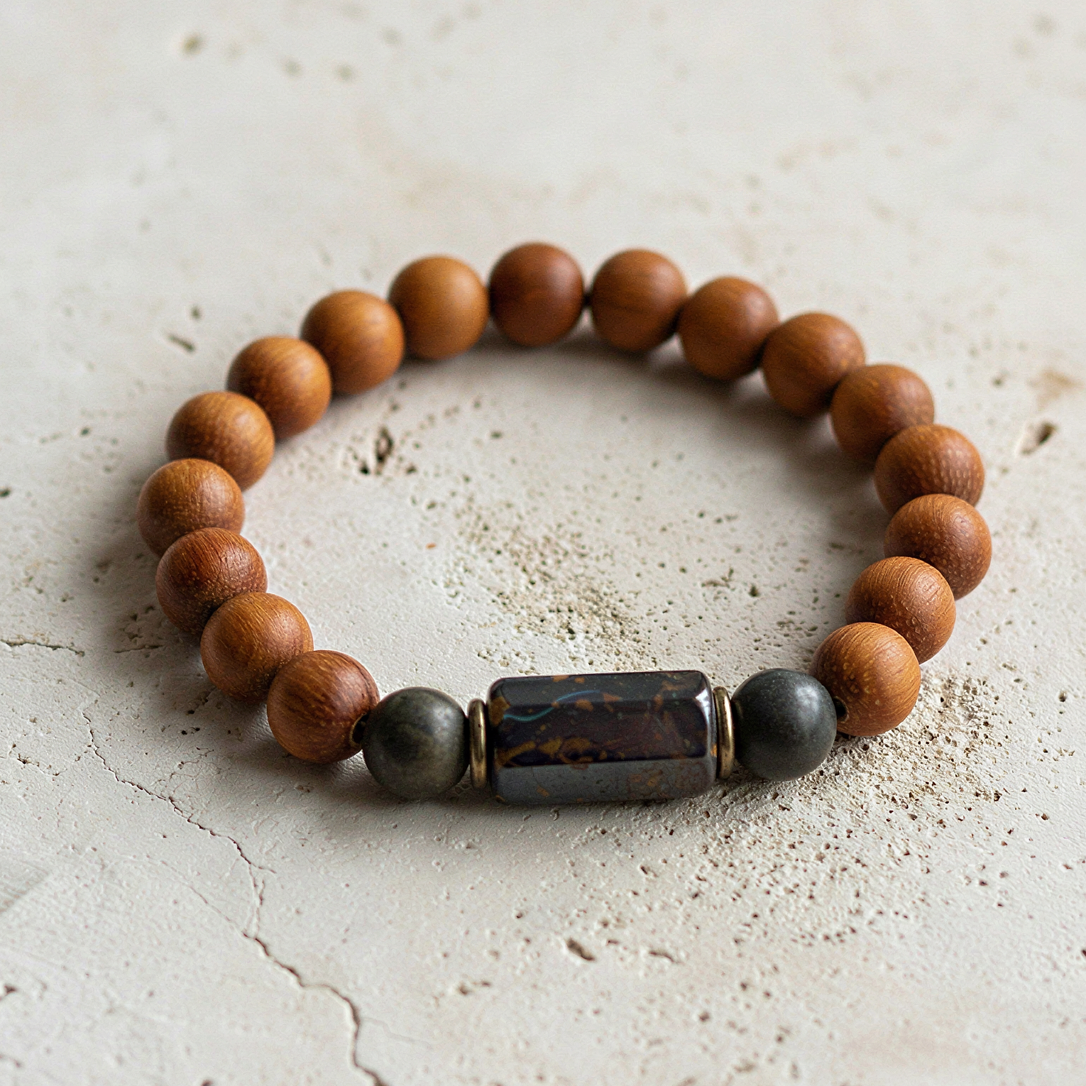 Bayong wood and boulder opal bracelet resting on natural stone with soft, diffused forest light