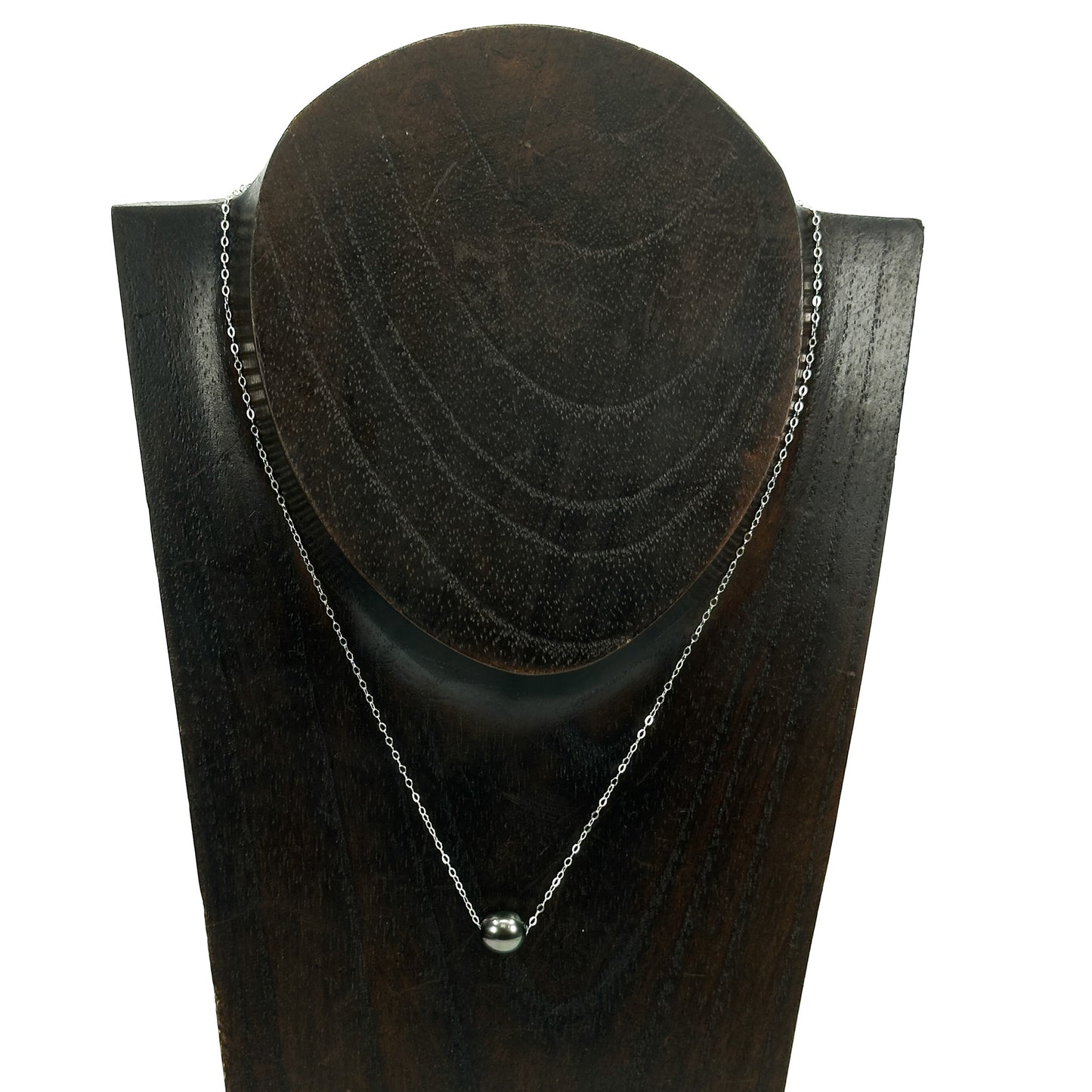 Silver necklace on a dark wooden stand with a white background