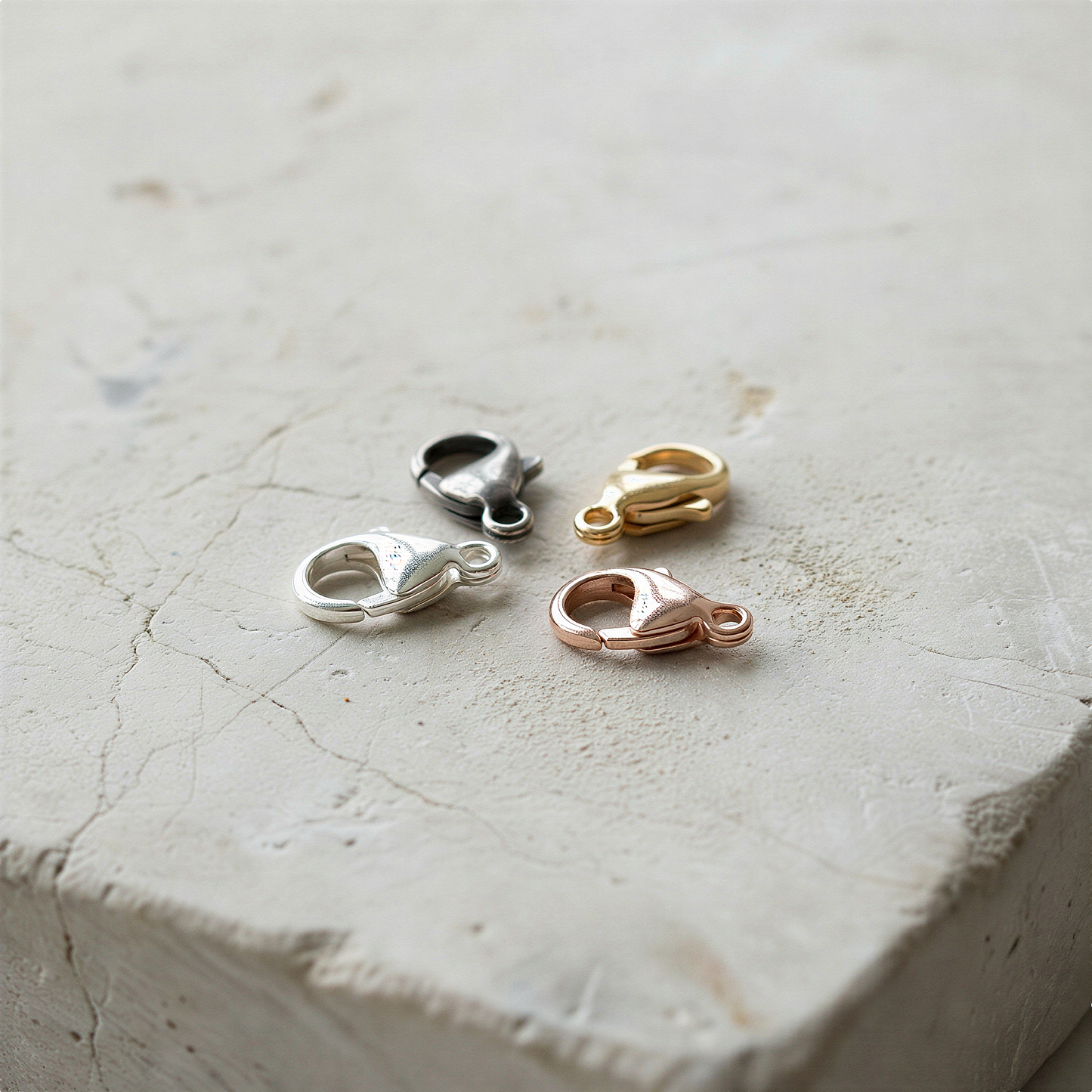 9mm oval lobster clasp in silver tones resting on stone with soft natural light and moss accents