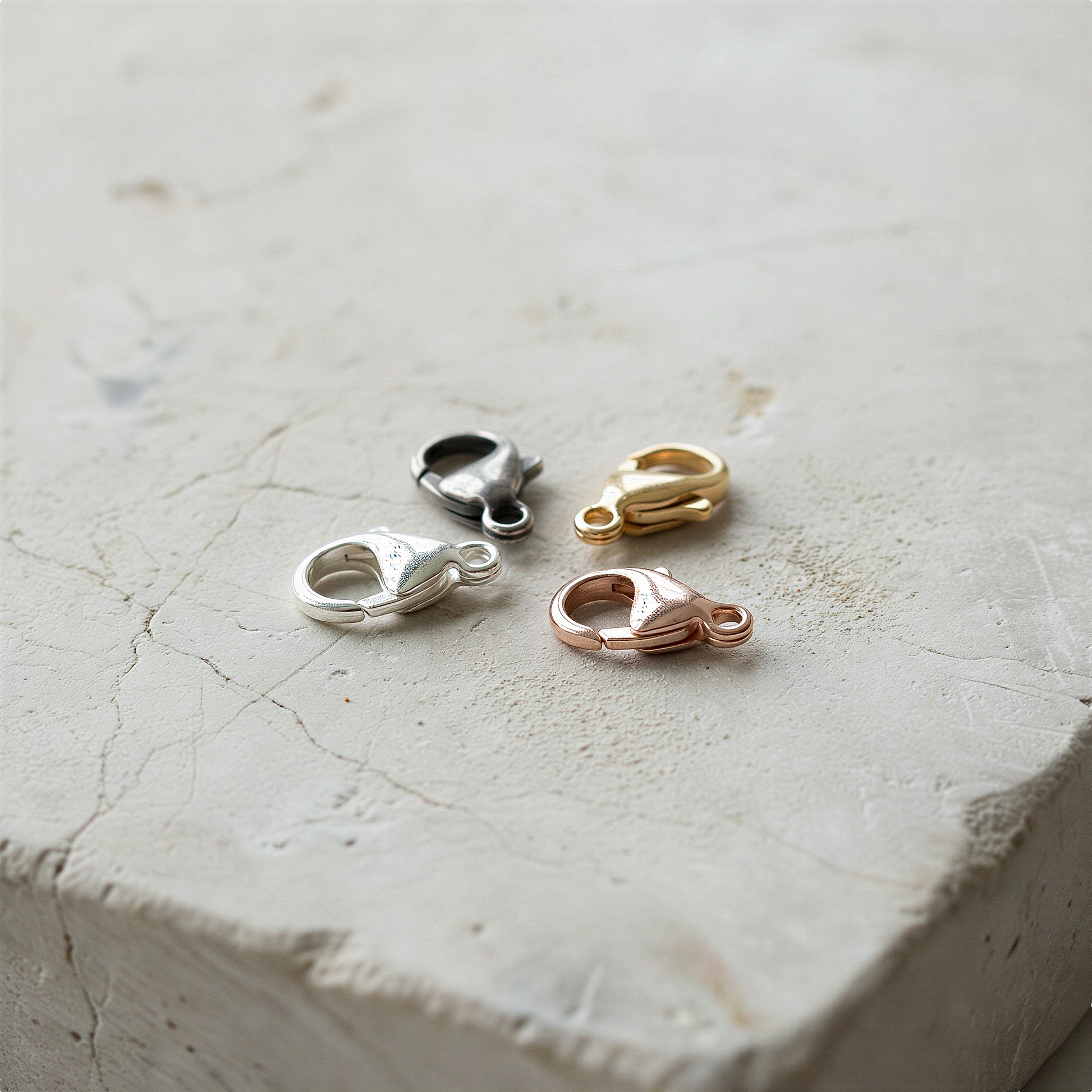 9mm oval lobster clasp in silver tones resting on stone with soft natural light and moss accents