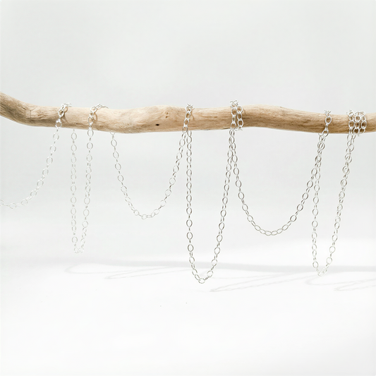 Small fluffy cable chain in silver and gold tones on neutral surface with refined, natural light