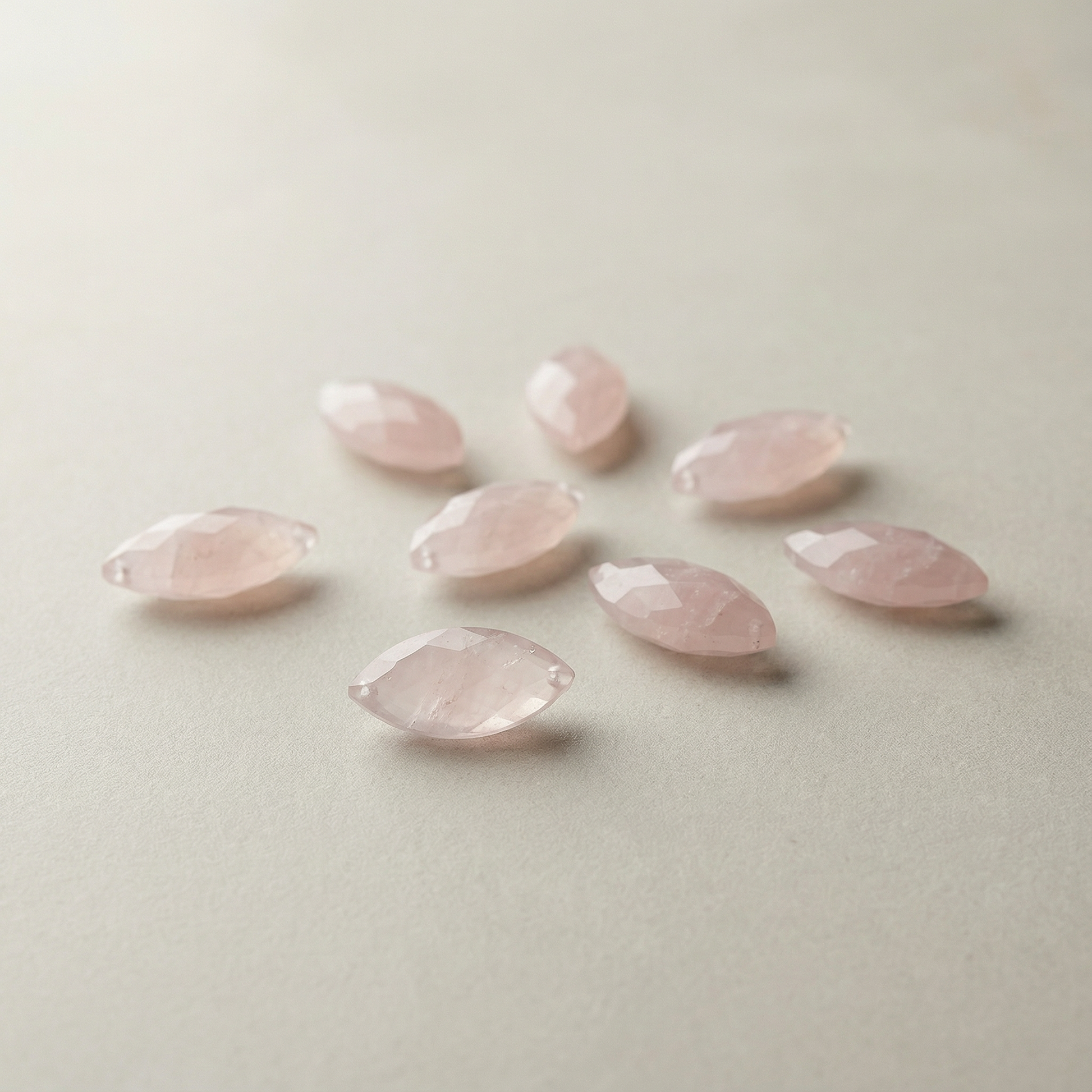 Faceted rose quartz marquise bead resting on soft neutral linen with diffused light and serene, balanced styling