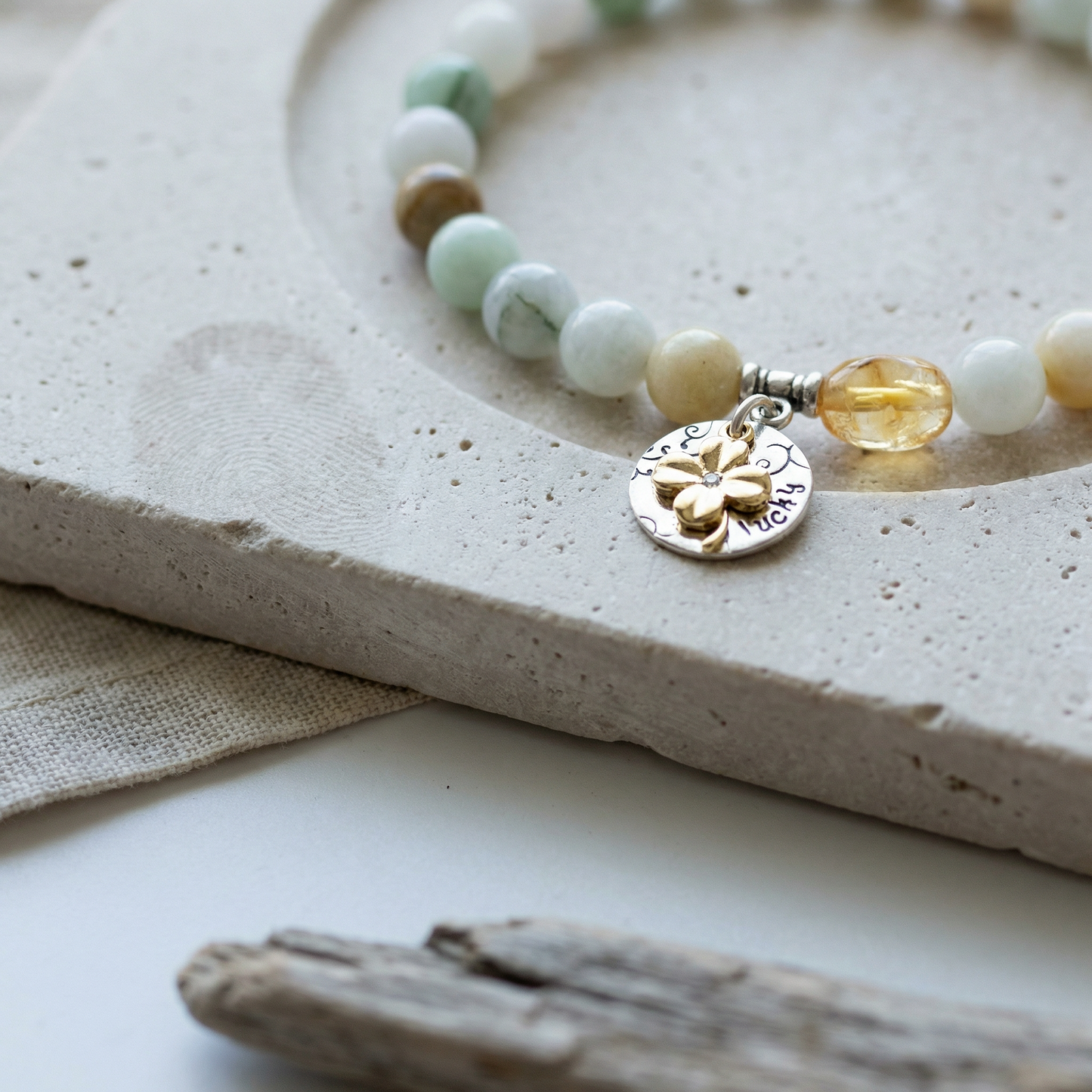 Jade and citrine bracelet on honed limestone with linen and driftwood, soft morning light.