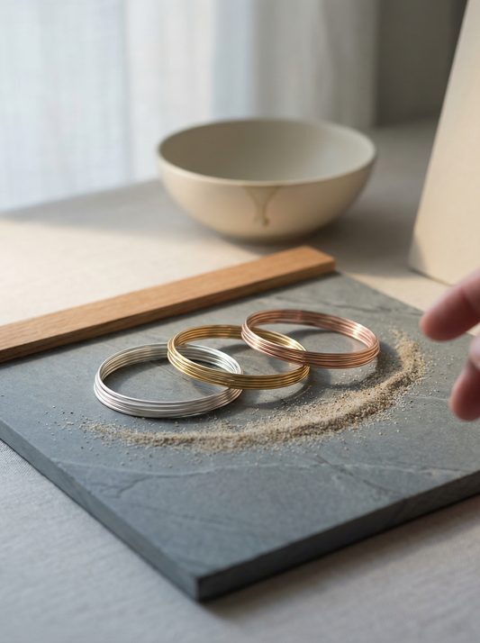 Three delicate jewelry wires on honed slate under soft linen‑filtered morning light.