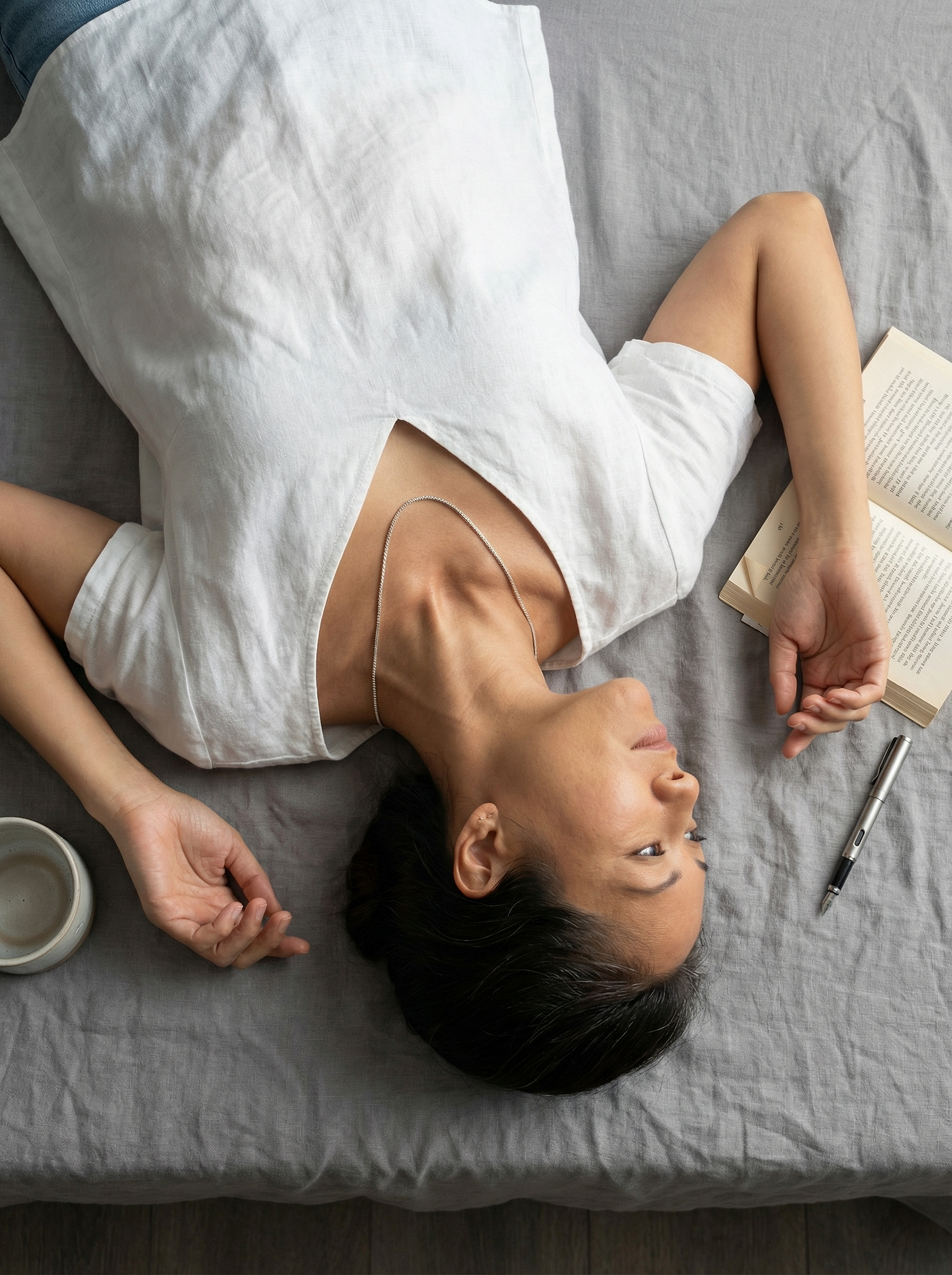 Overhead view of reclining model with sterling silver box chain and linen still life.